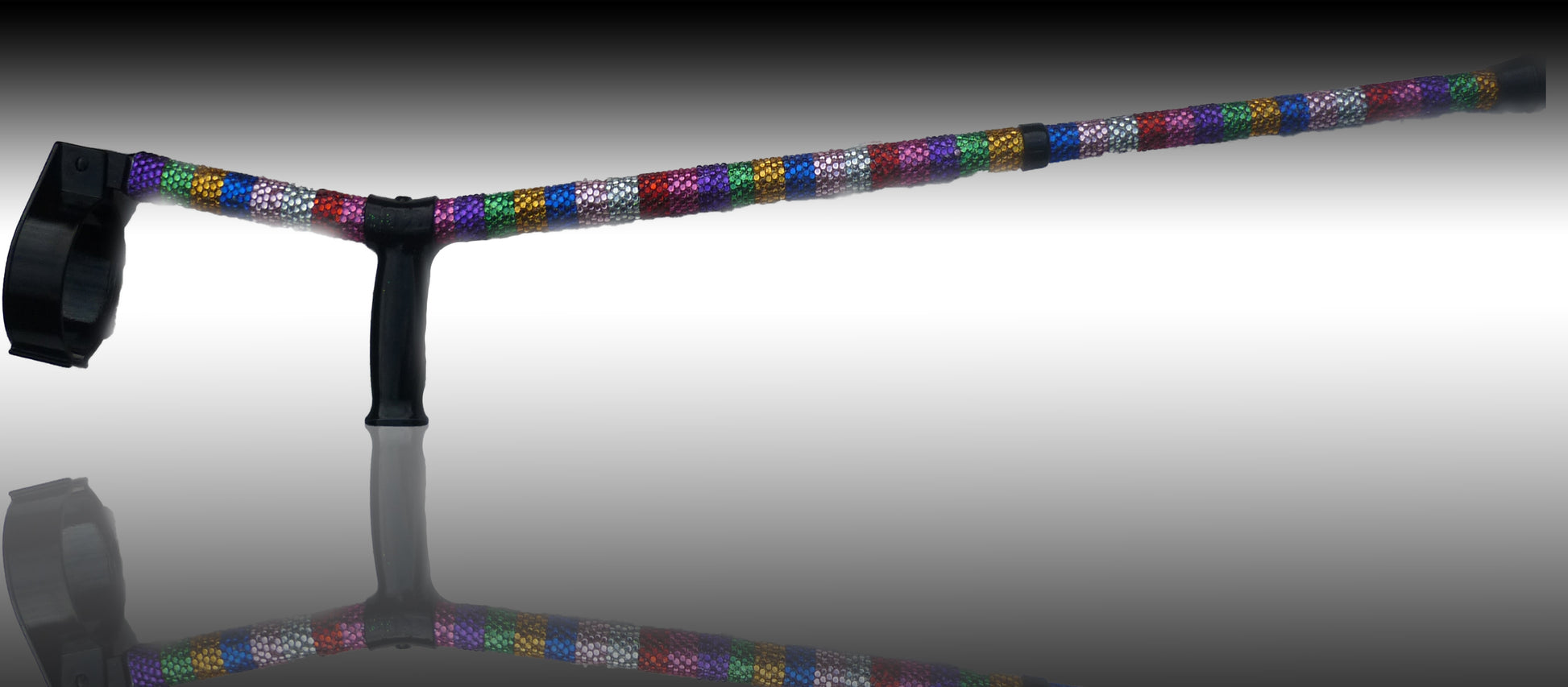 Juicy Lucy Crutch on reflective material showing a reflection. The crutch has rows of colours Rhinestones down.