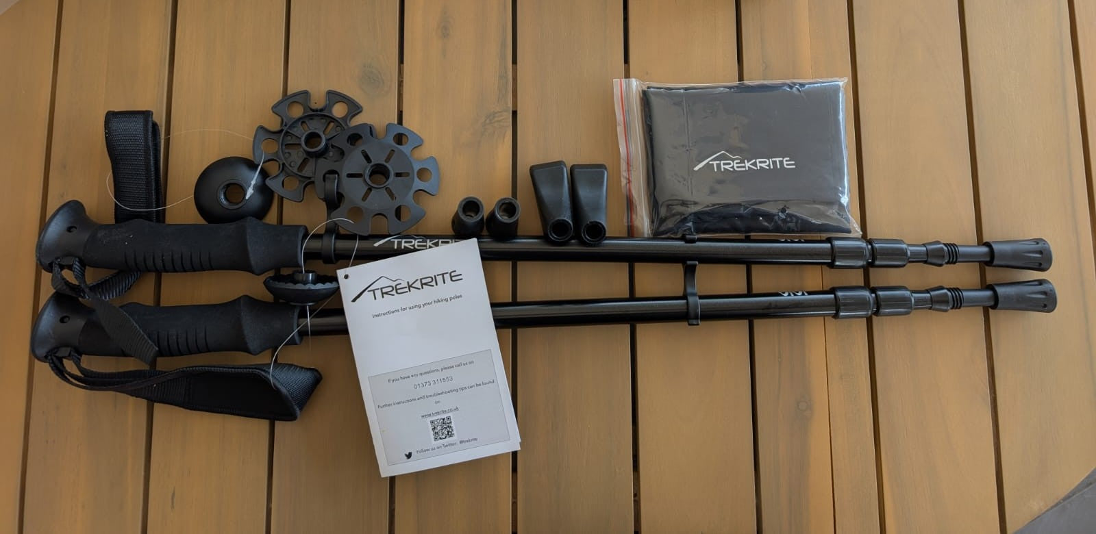 Black trekking poles with accessories on a wooden surface
