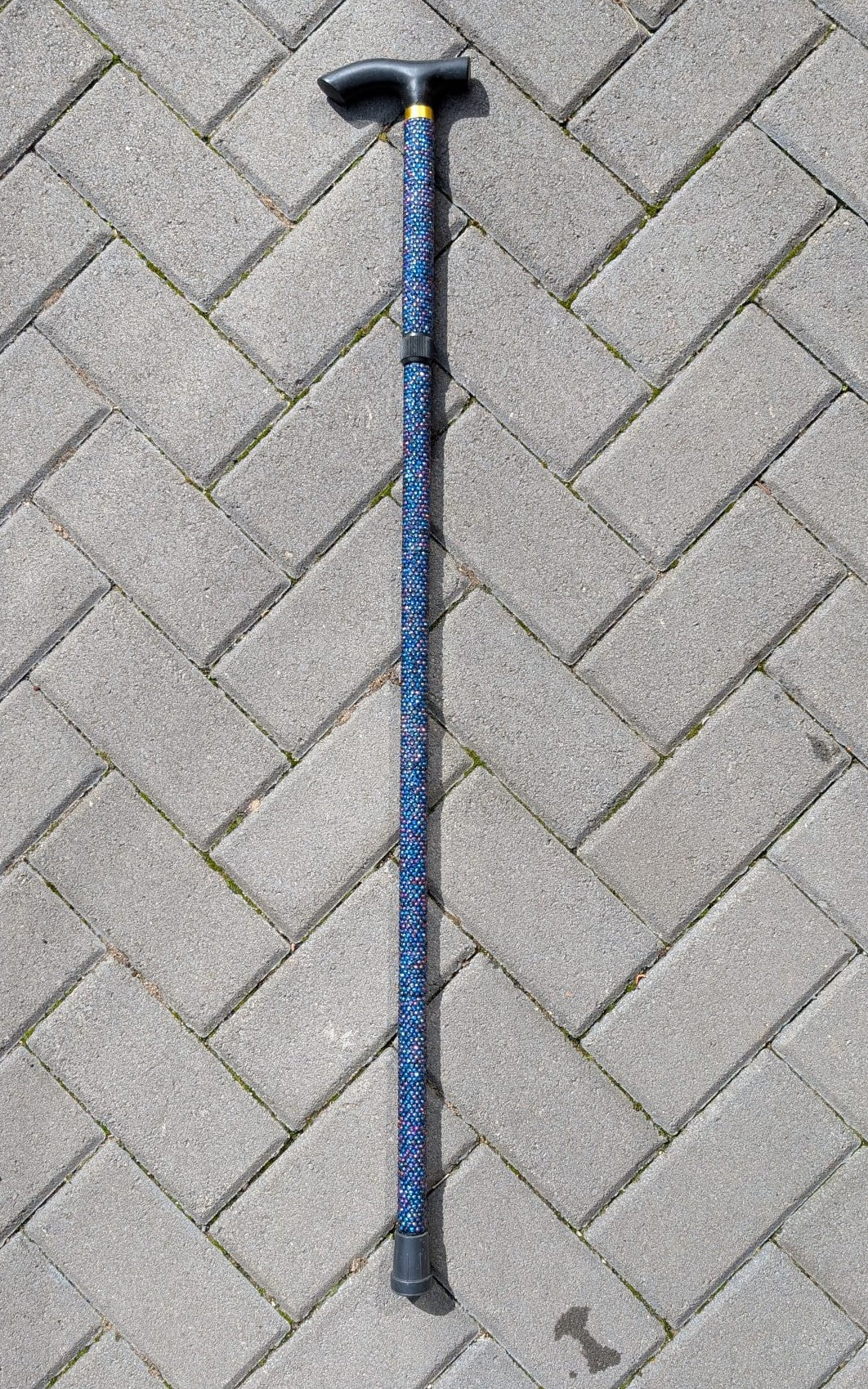 Walking Stick in blue rhinestones against a brick background