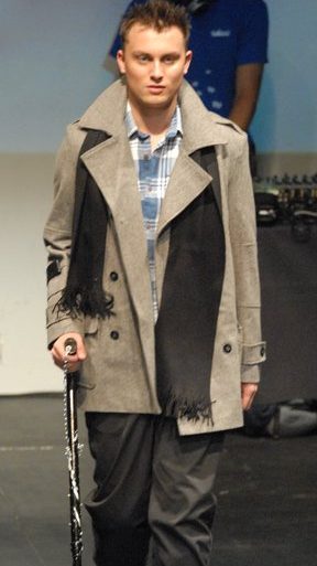 A man with short hair wearing a beige jacket using the Punk Crutch in his hand.